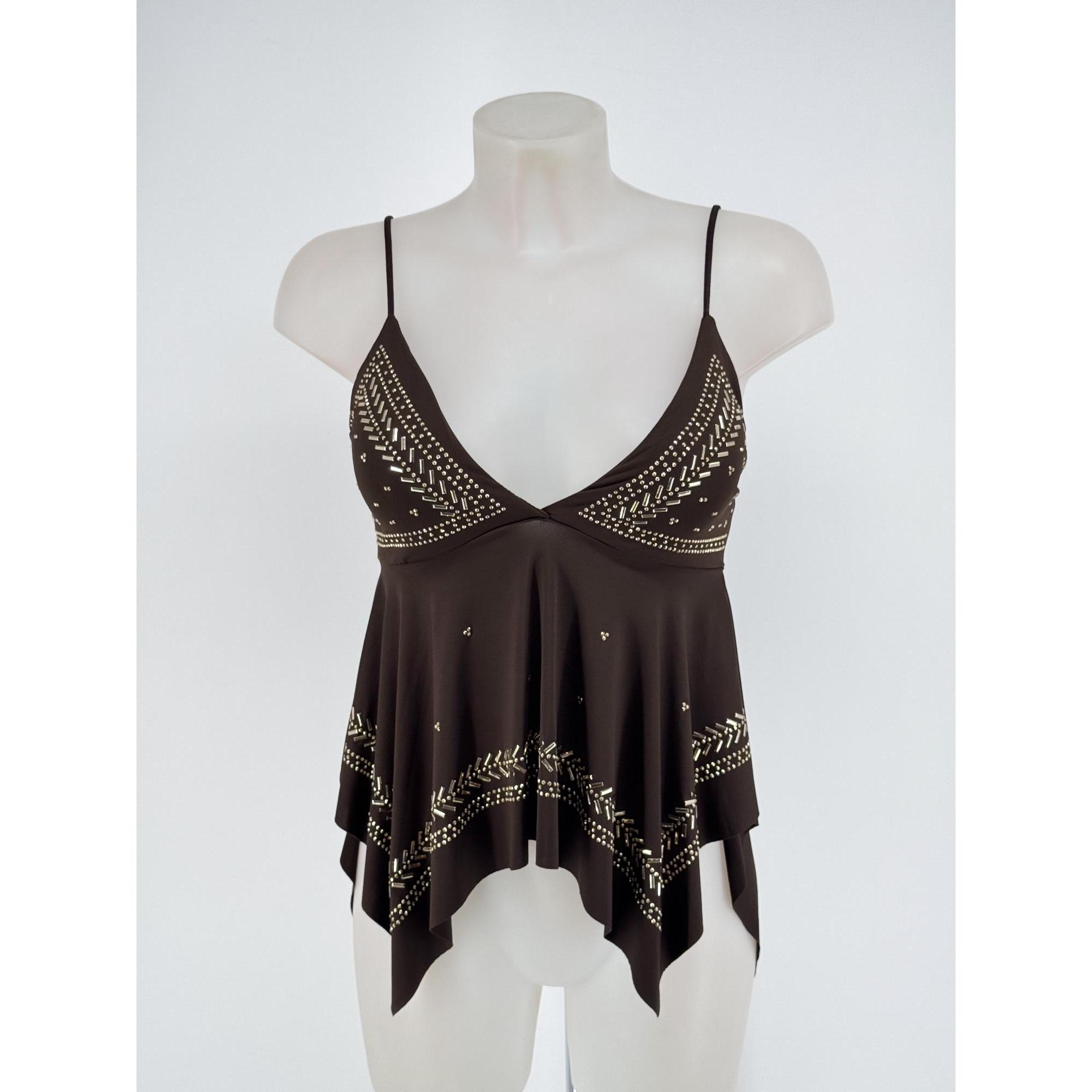 Top de tirantes para mujer con escote en pico pronunciado, tirantes finos regulables, elegante bajo asimétrico en picos y llamativos detalles de tachuelas y apliques metálicos dorados. Disponible en varios colores ideales para un look casual, boho o fiest