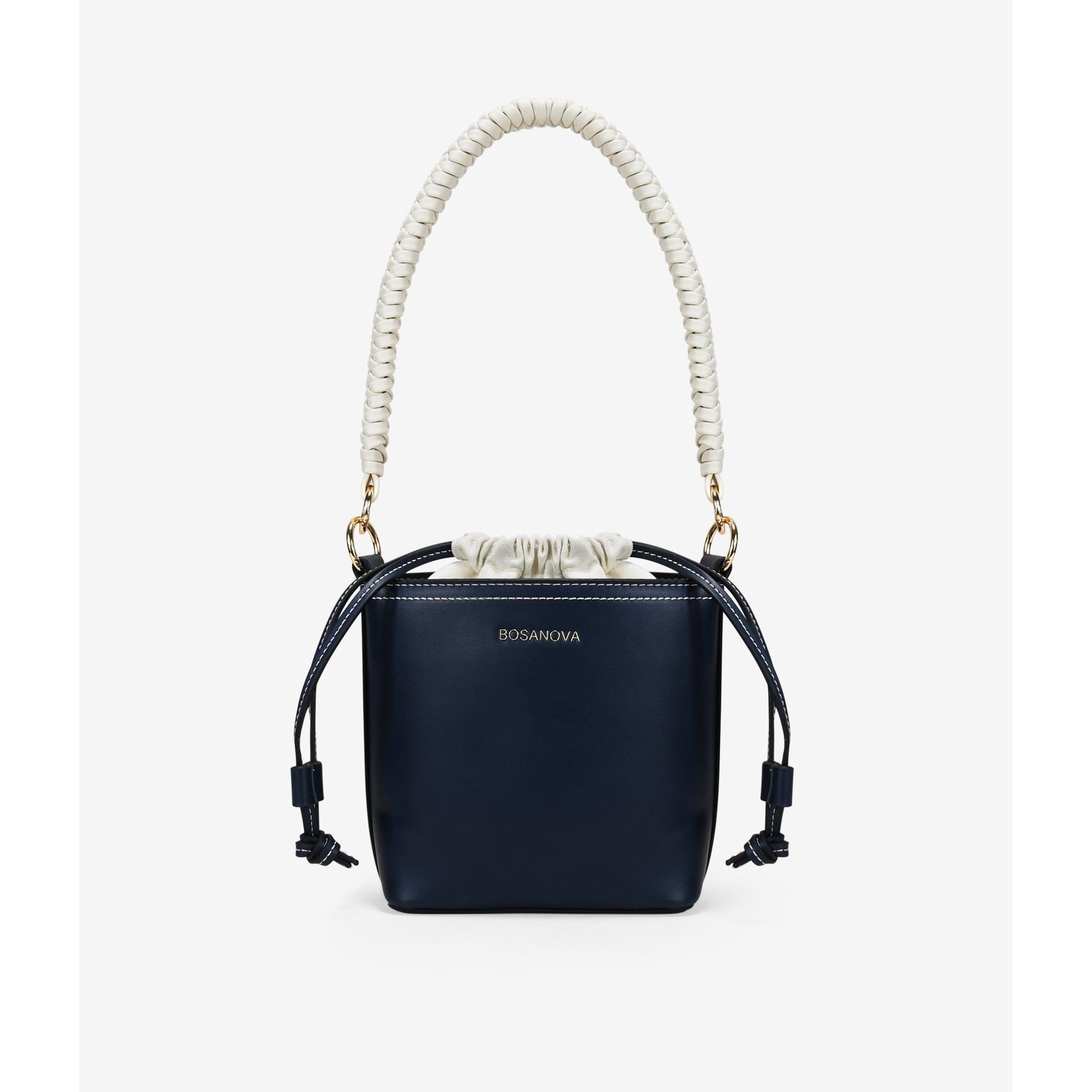 Bosanova Bolso cubo pequeño para mujer con asa de mano trenzada y asa de cruzar regulable. Bolsa interior en canvas y cierre con lazo fruncido.