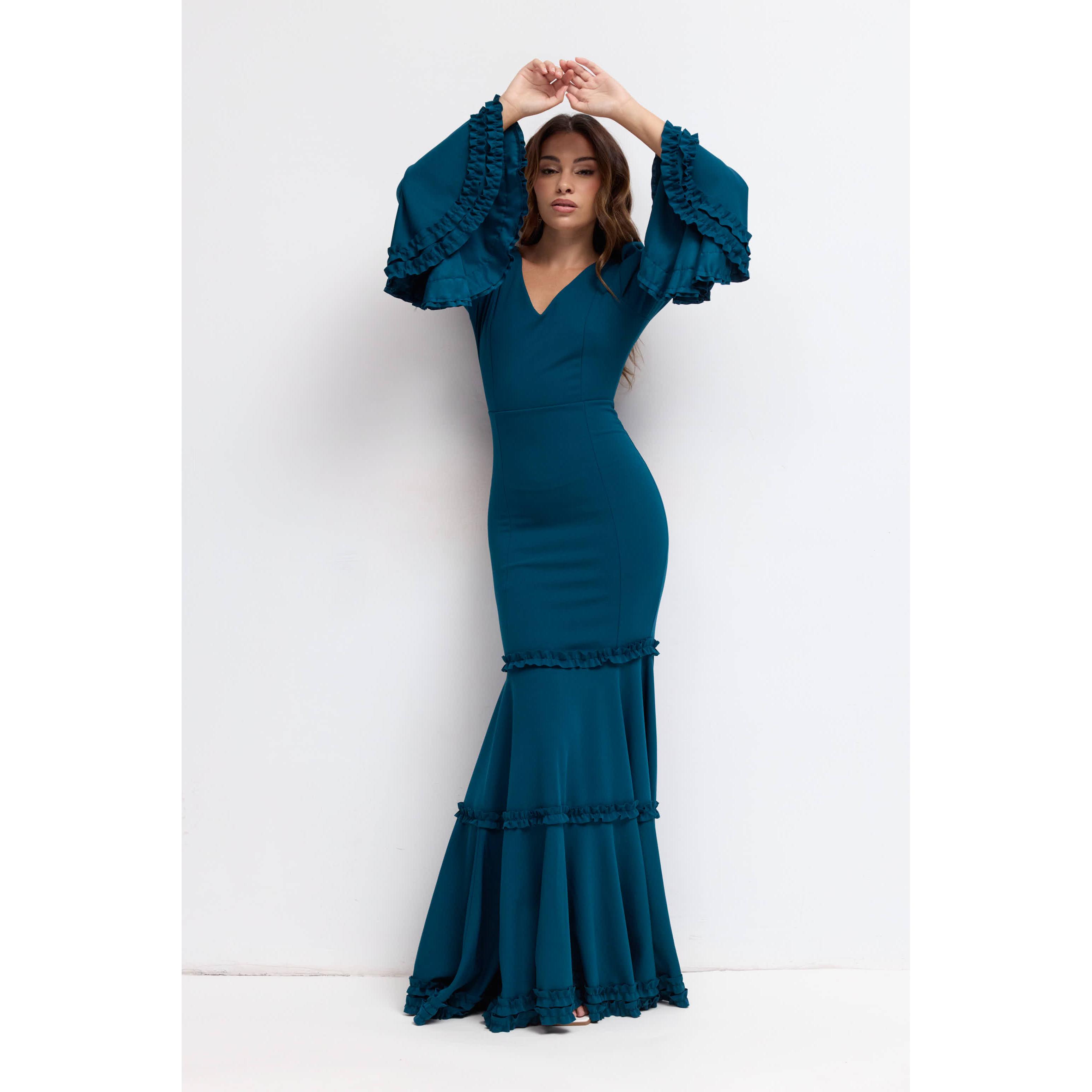 Vestido largo de fiesta en tejido scuba crepe para invitada o eventos. Diseño entallado sirena con escote en V, mangas acampanadas con volantes y falda con volantes escalonados. Disponible en varias tallas y tonos para deslumbrar en tu ocasión especial.