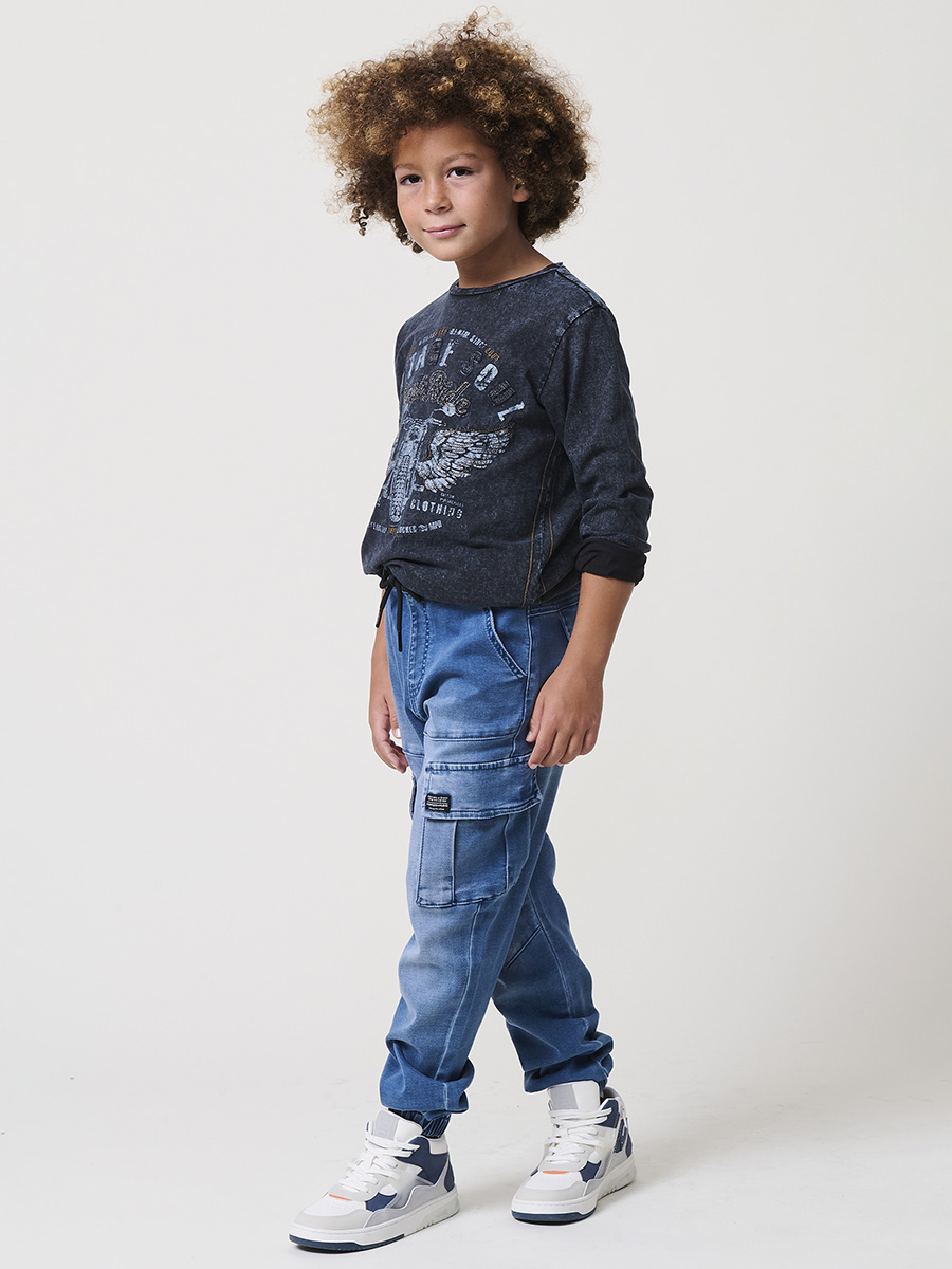 Koroshi - Pantalón jogger niño en knit denim elástico 100% algodón con acabado lavado azul medio y bolsillos cargo funcionales para cole y tiempo libre